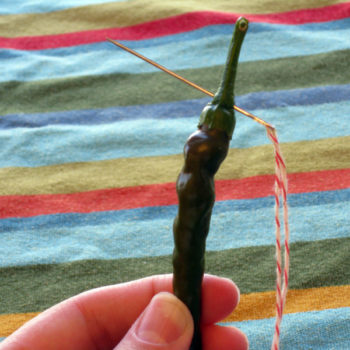 Thread the pepper through the stem, rather than the flesh of the pepper