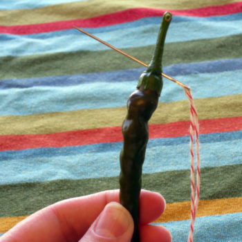 Thread the pepper through the stem, rather than the flesh of the pepper